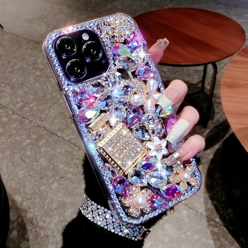 Hand holding a smartphone with a bejeweled, decorative case