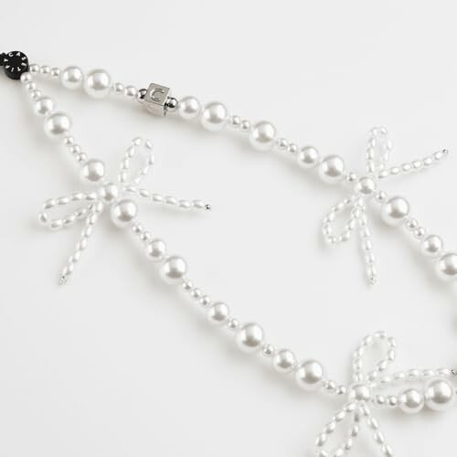 Pearl necklace with bow design on white background