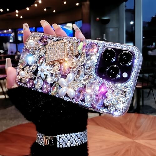 Hand holding a phone with a jeweled and sparkly case